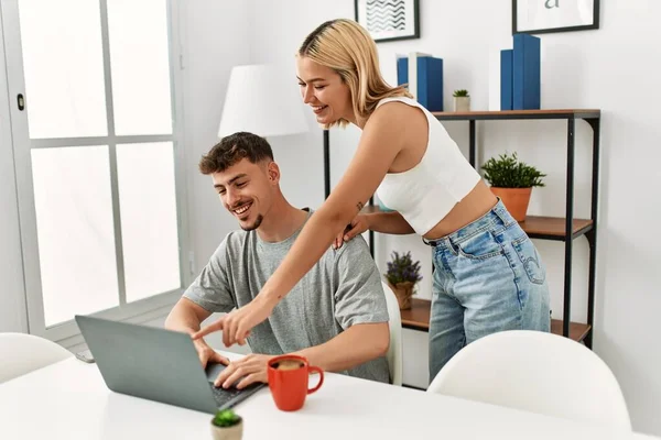 年轻的高加索夫妇坐在家里的桌子上 一边用笔记本电脑一边喝咖啡 — 图库照片