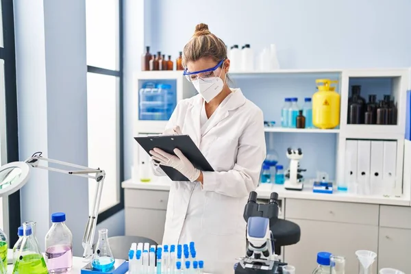 Giovane Donna Bionda Con Uniforme Scienziato Maschera Medica Che Scrive — Foto Stock