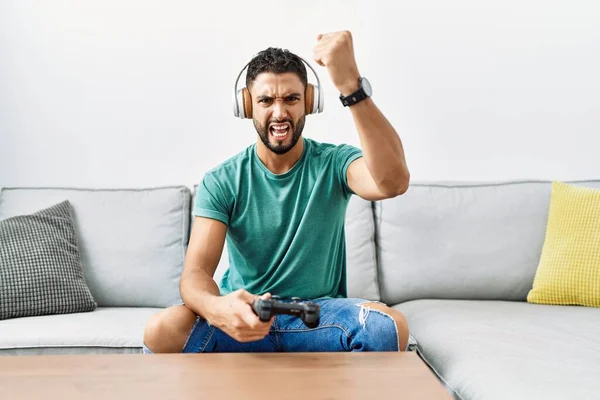 Pohledný Hispánský Muž Sluchátkách Při Hraní Videohry Drží Ovladač Otrávený — Stock fotografie