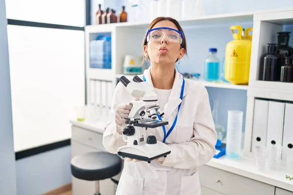 Joven Morena Trabajando Laboratorio Científico Con Microscopio Mirando Cámara Soplando — Foto de Stock