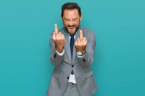 Middle age man wearing business clothes showing middle finger doing fuck you bad expression, provocation and rude attitude. screaming excited