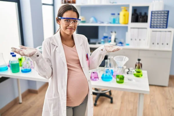 科学研究所で働いている若い妊婦は 腕と手で混乱した表情を上げました 疑わしい概念 — ストック写真