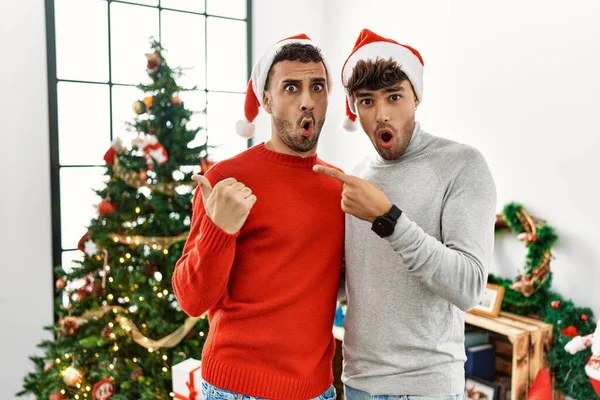 Genç Eşcinsel Çift Noel Ağacının Yanında Dikilmiş Şapkalarını Takmış Şaşırmış — Stok fotoğraf