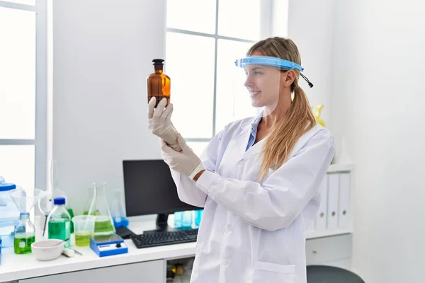 Joven Mujer Rubia Vistiendo Uniforme Científico Buscando Botella Laboratorio — Foto de Stock