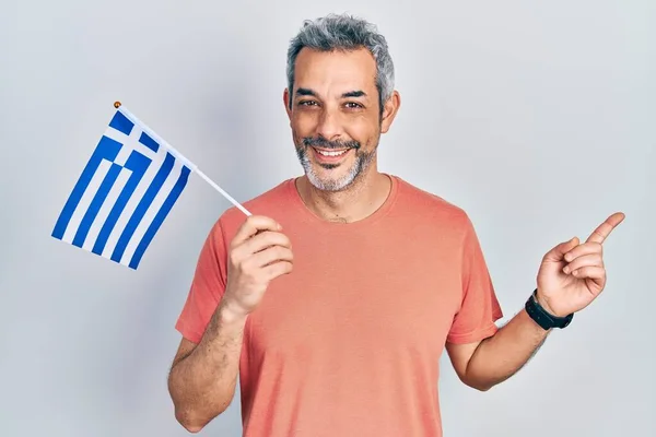 Przystojny Mężczyzna Średnim Wieku Siwymi Włosami Trzymający Grecką Flagę Uśmiechnięty — Zdjęcie stockowe