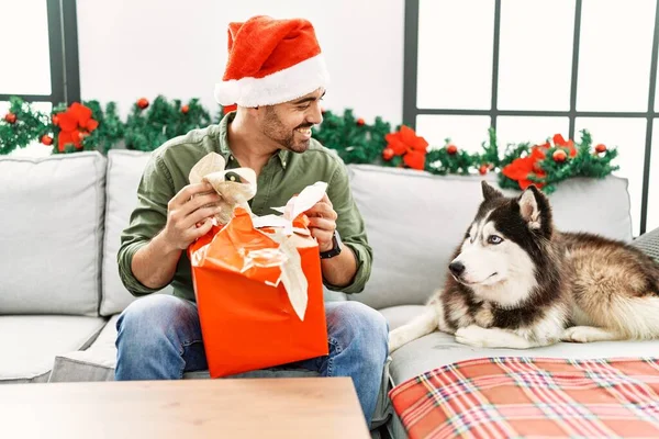 Jovem Hispânico Homem Unboxing Presente Sentado Sofá Com Cão Por — Fotografia de Stock