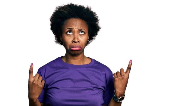 アフリカ系アメリカ人の女性とアフロの髪を着てカジュアルな紫色のTシャツを指している悲しいと動揺 指で方向を示す 不幸なと落ち込んで — ストック写真