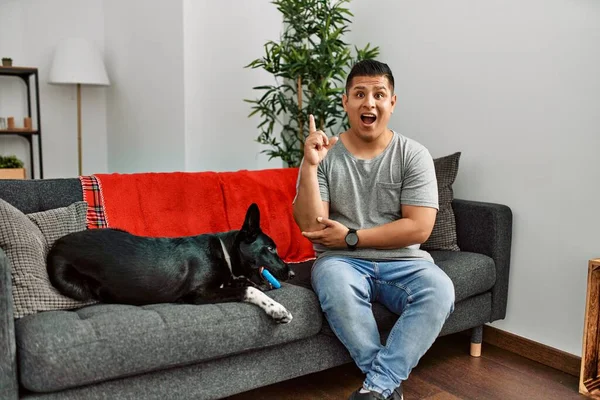 Jovem Latino Homem Cão Sentado Sofá Casa Apontando Dedo Para — Fotografia de Stock