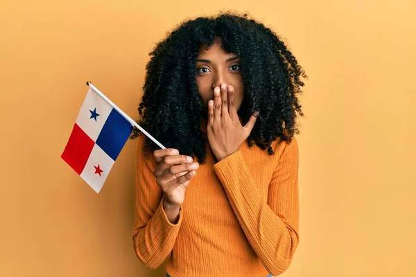アフロヘアのアフリカ系アメリカ人女性は 手で口を覆い ショックを受け 間違いを恐れてパナマの旗を持っていた 驚きの表情 — ストック写真