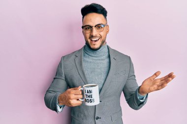 Genç Arap adam ben patron kahve fincanıyım başarıyı mutlu bir gülümsemeyle ve kazanan yüz ifadesiyle kutluyorum. 