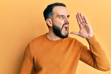 Sakallı genç adam, sıradan bir kazak giyip el ele tutuşarak bağırıyor ve bağırıyordu. iletişim konsepti. 