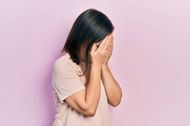 Orta yaşlı İspanyol kadın, günlük kıyafetler giyip ağlarken suratını ellerle kapatıyor. depresyon kavramı. 