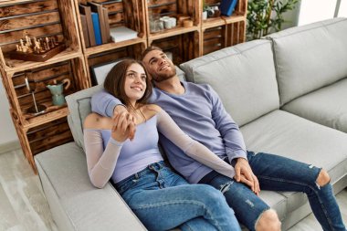 Kafkasyalı genç çift koltukta rahatça oturup evlerinde sarılıyorlar..