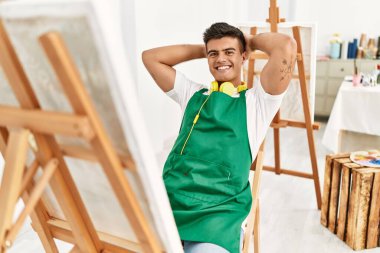 Genç İspanyol adam gülümsüyor. Kendine güveni tam. Sanat stüdyosunda elleri başının üstünde rahatlamış.