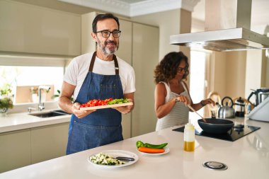 Orta yaşlı bir çift evde Akdeniz yemeği pişiriyor. Gülümsüyor, yan tarafa bakıyor ve düşünüyor.. 