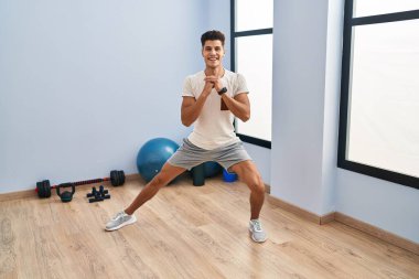 Genç İspanyol adam gülümsüyor spor merkezinde esniyor.