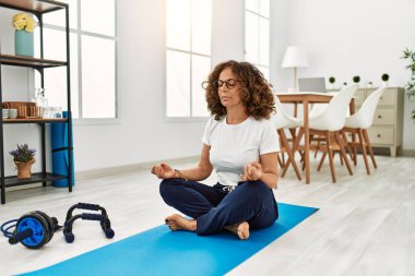 Orta yaşlı İspanyol kadın evde yoga eğitimi veriyor.