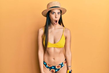 Genç İspanyol kadın bikini ve yaz şapkası takıyor. Şaşırmış ve korkmuş bir ifade, korku ve heyecanlı bir yüz ifadesi var.. 