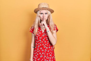 Sarışın, yaz şapkası takan, dudakları parmaklı, sessiz olmak isteyen güzel beyaz bir kadın. sessizlik ve gizli konsept. 
