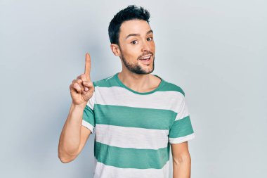 Gündelik kıyafetler giyen genç İspanyol adam başarılı bir fikirle işaret ediyor. Heyecanlı ve mutlu. Bir numara.. 