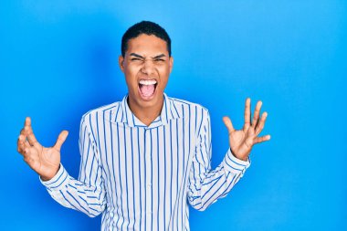 Genç Afro-Amerikalı, günlük kıyafetler giymiş deli deli deli bağırıyor ve agresif bir ifade ve kollarla bağırıyor. hüsran kavramı. 