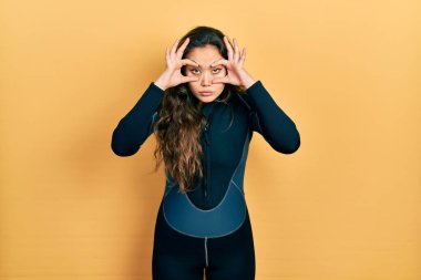 Genç İspanyol kız dalgıç neoprene üniforması giyiyor. Gözlerini parmaklarıyla açmaya çalışıyor. Uykulu ve yorgun. 