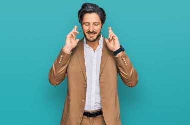 İş kıyafetleri giymiş genç İspanyol adam umut ve gözlerin kapalı bir şekilde şans diliyor. Şans ve batıl inançlar. 