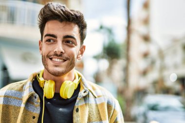 Yakışıklı İspanyol adam, mutlu ve kendine güvenen, kulaklık takan, modern tarzda gülümseyen.