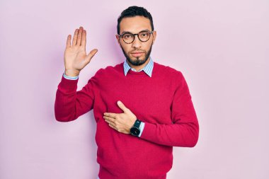 Sakallı, iş gömleği giyen, gözlüklü göğüs ve avuç içi açık küfür eden, sadakat yemini eden İspanyol bir adam. 