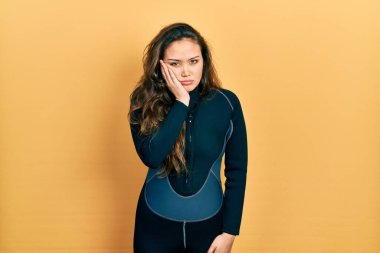 Genç İspanyol kız dalgıç neoprene üniforması giyiyor ve kolları çapraz depresyondan sıkılmış ve yorgun görünüyor.. 