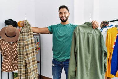 Genç Arap müşteri kıyafet mağazasında kendine güvenen bir alışveriş yapıyor.