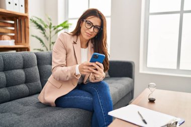 Genç İspanyol kadın psikolog psikoloji merkezinde akıllı telefon kullanıyor.