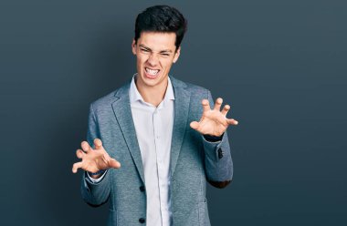 Genç İspanyol bir adam iş kıyafetleri giyip gülümsüyor. Pençe hareketlerini kedi gibi yapıyor. Agresif ve seksi bir ifade. 