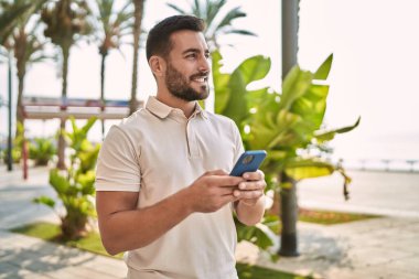 Sokakta akıllı telefon kullanan, kendine güvenen genç bir İspanyol.