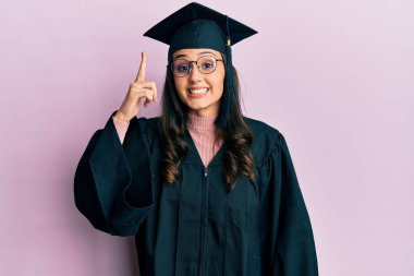 Mezuniyet şapkası ve tören cübbesi takan genç İspanyol kadın başarılı bir fikri işaret ediyor. Heyecanlı ve mutlu. Bir numara.. 