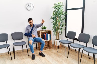 Kol askısı ve parmağıyla kliniğin bekleme odasında oturan genç Arap adam acı çekiyor.