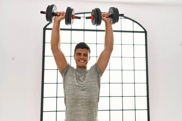 Jovem Hispânico Sorrindo Treinamento Confiante Usando Halteres Centro Esportivo — Fotografia de Stock