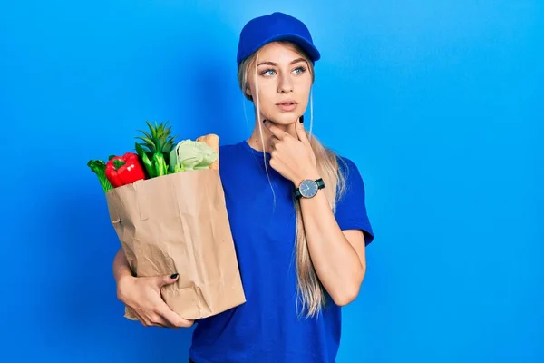 年轻的高加索女人穿着信使制服 带着超市里的食品杂货 摸着疼痛的脖子 喉头因流感 凝块和感染而疼痛 — 图库照片