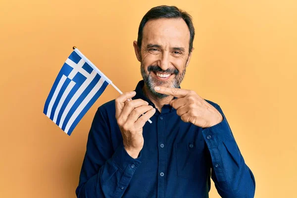 Homem Hispânico Meia Idade Segurando Bandeira Grega Sorrindo Feliz Apontando — Fotografia de Stock