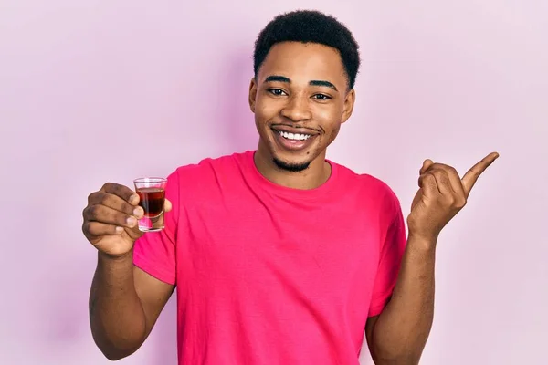 Joven Hombre Afroamericano Bebiendo Whisky Disparo Sonriendo Feliz Señalando Con — Foto de Stock