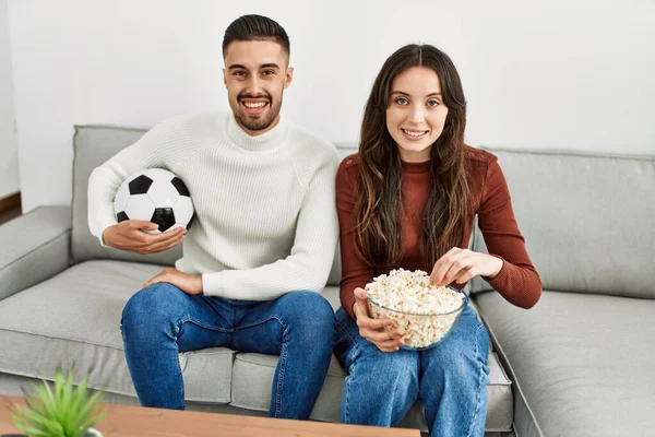 Młoda Latynoska Para Ogląda Mecz Piłki Nożnej Jedząca Popcorn Domu — Zdjęcie stockowe