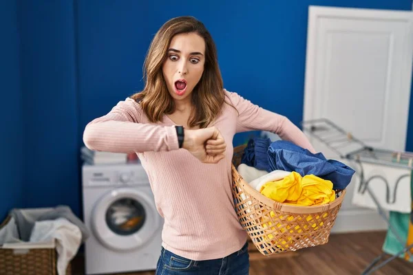 Young Woman Holding Laundry Basket Looking Watch Time Worried Afraid — Stockfoto
