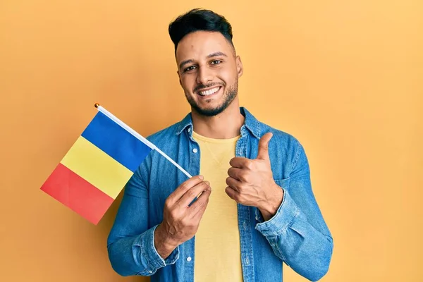 Joven Árabe Sosteniendo Bandera Romania Sonriendo Feliz Positivo Pulgar Hacia —  Fotos de Stock