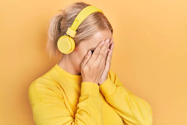 Mujer Rubia Joven Escuchando Música Usando Auriculares Con Expresión Triste —  Fotos de Stock
