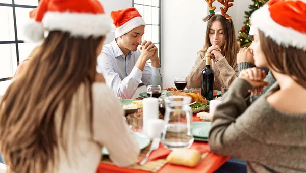 Grupa Młodych Ludzi Świętujących Boże Narodzenie Modlących Się Jedzenie Siedzące — Zdjęcie stockowe