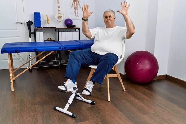 Starszy Kaukaski Mężczyzna Fizjoterapia Klinika Pomocą Pedał Ćwiczenia Pokazuje Wskazując — Zdjęcie stockowe