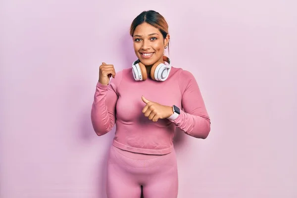 Beautiful Hispanic Woman Wearing Gym Clothes Using Headphones Pointing Back — Stok fotoğraf