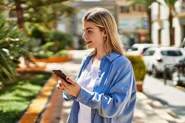 若いですブロンド女の子笑顔幸せな使用スマートフォンで街 — ストック写真