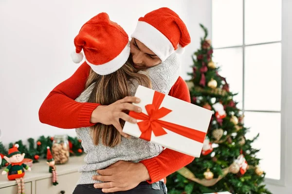 Casal Jovem Abraçando Sorrindo Feliz Usando Chapéu Natal Segurando Presente — Fotografia de Stock