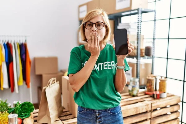 Middelbare Leeftijd Blonde Vrouw Werken Dragen Vrijwilliger Shirt Tonen Smartphone — Stockfoto